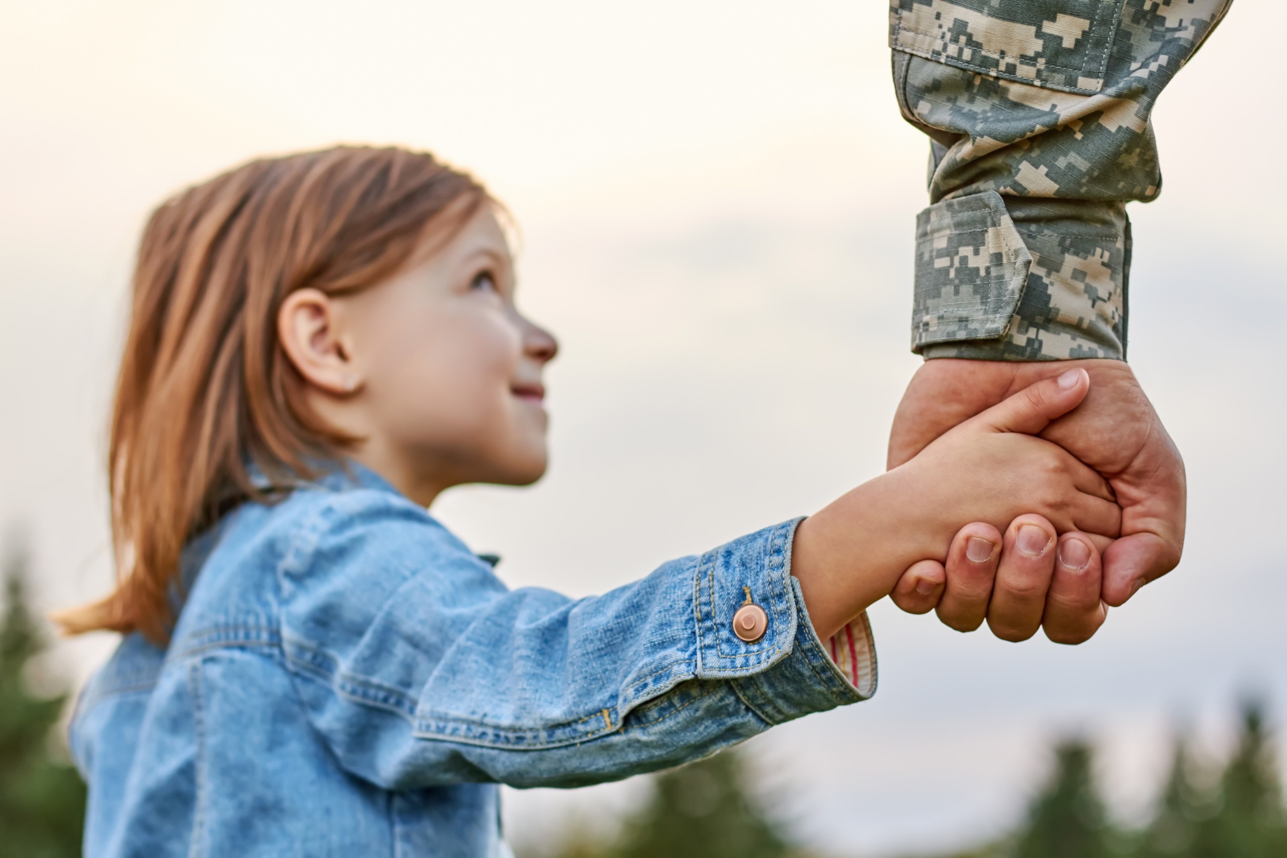 girl holding hand of male adult wearing camo